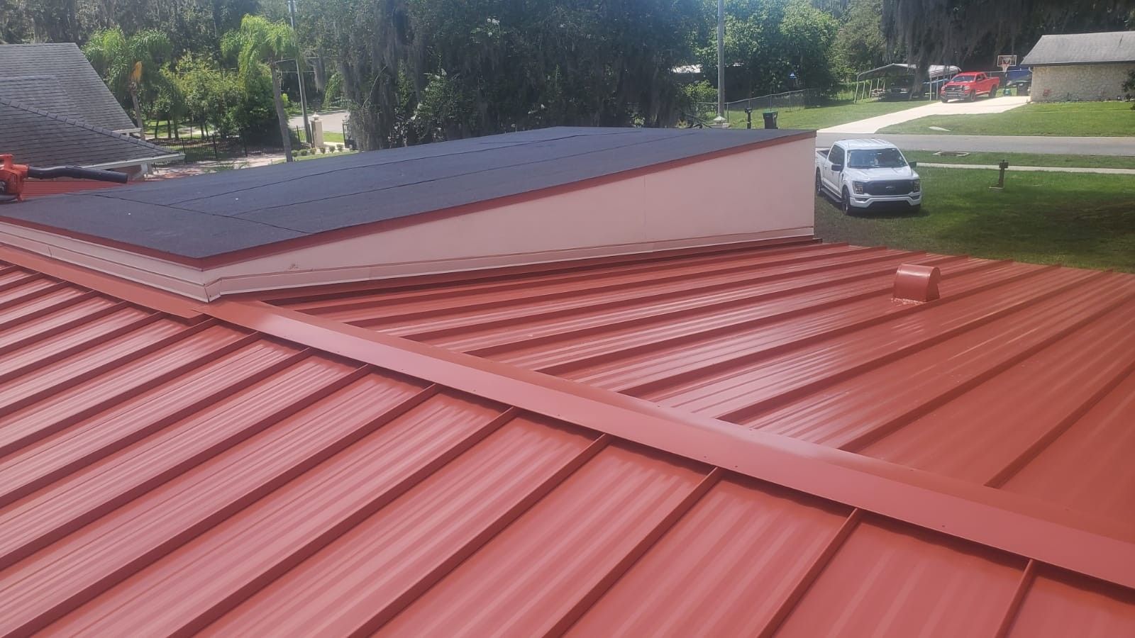 Red metal roof with skylight, white trim, and a truck parked outside.