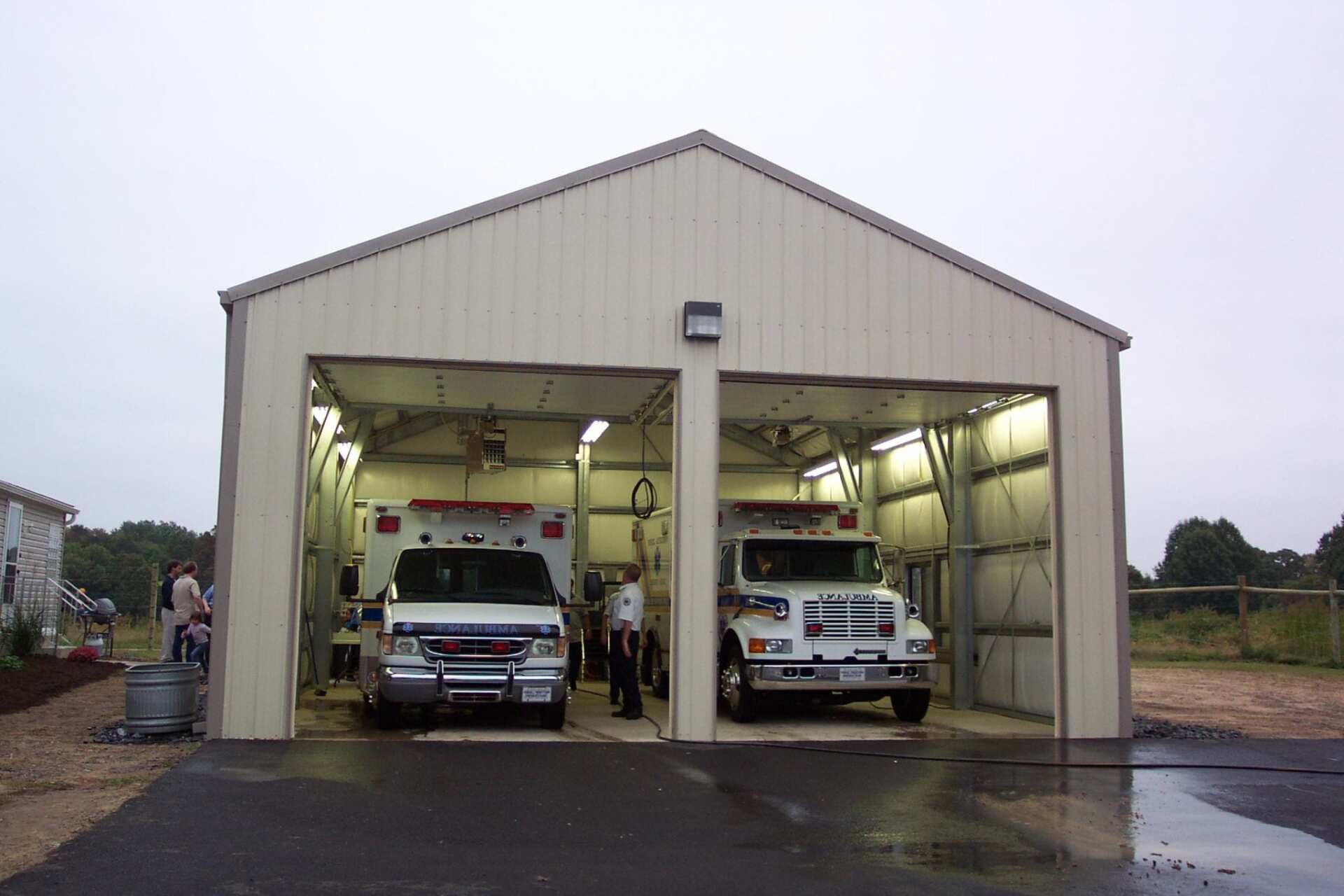 Two ambulances inside a metal garage with open doors.