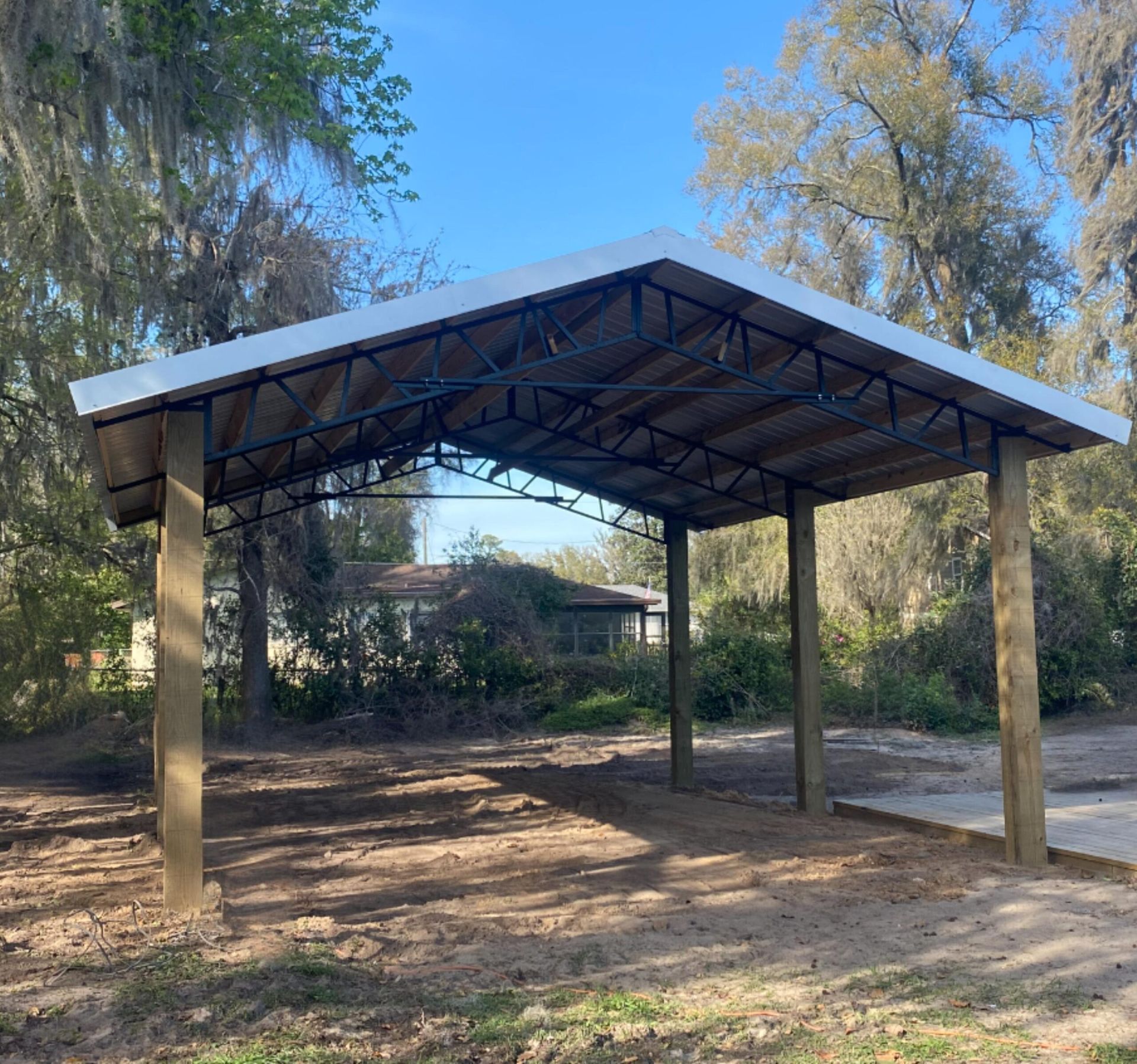Carport with wooden posts and metal roof in a yard.