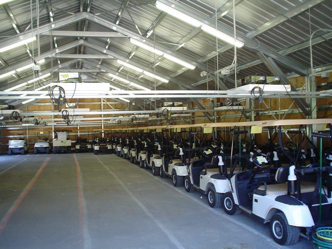Row of white golf carts parked in a covered garage.
