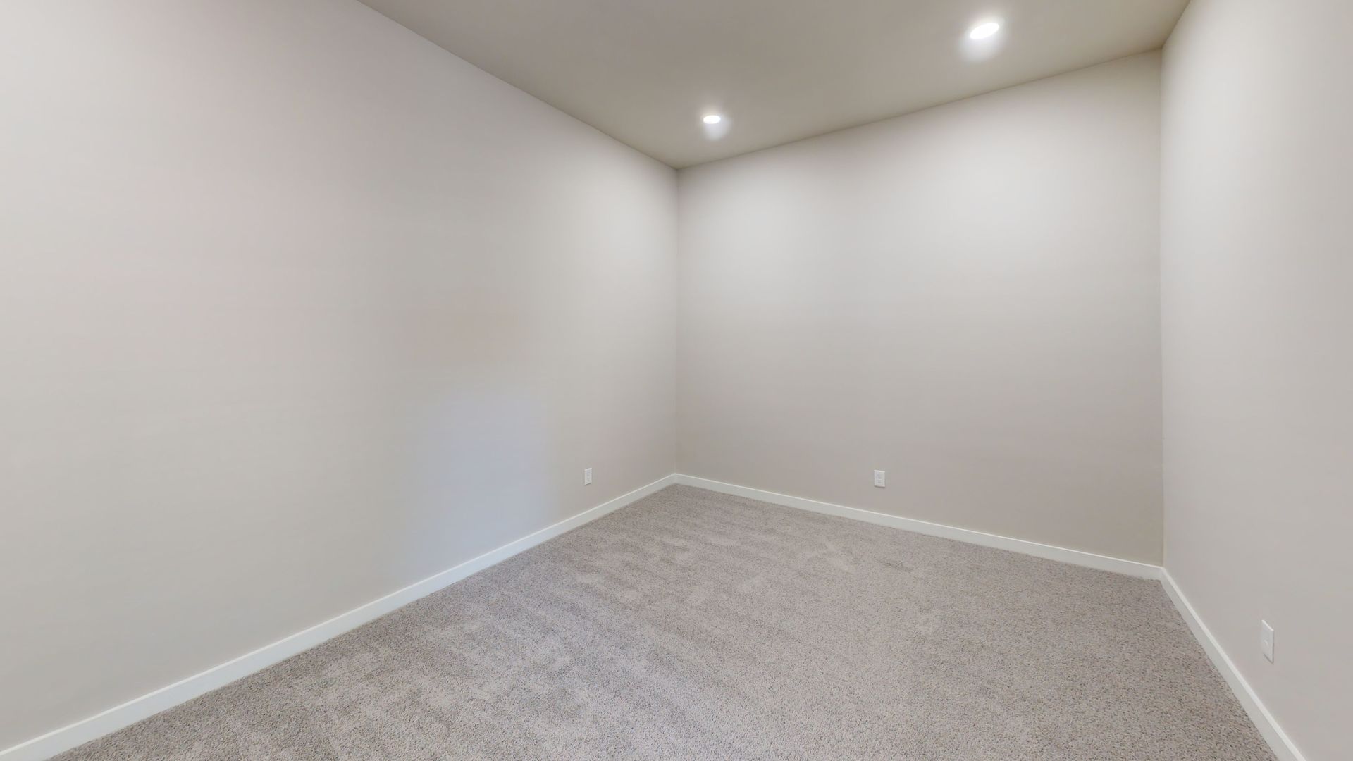 Empty carpeted room with light gray walls and recessed ceiling light