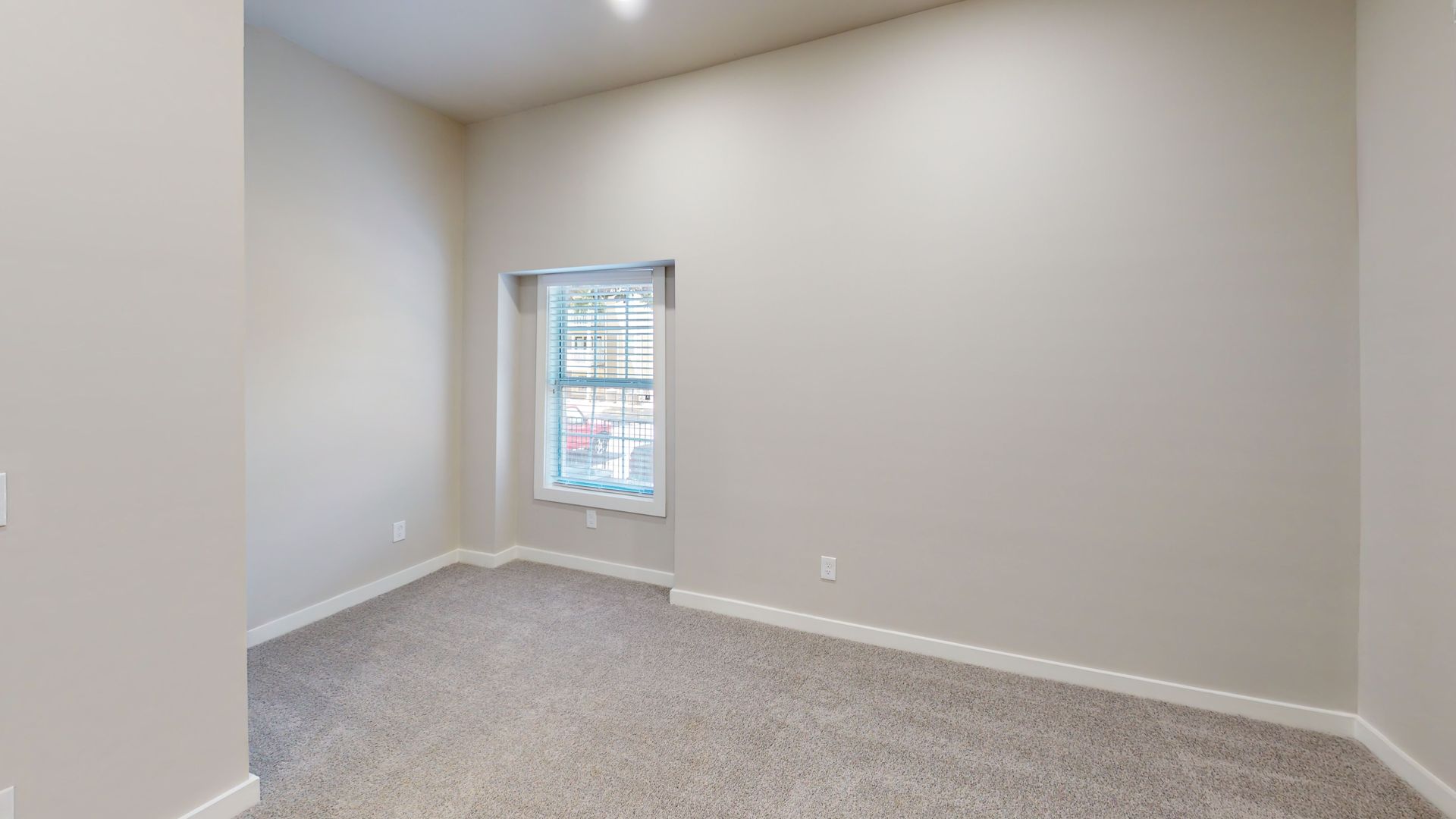 Empty beige bedroom with carpet and a small window
