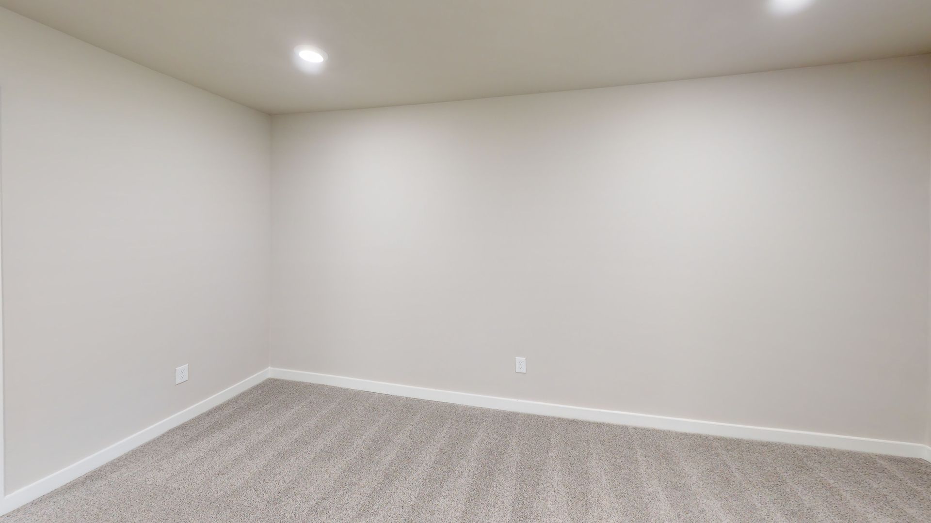 Empty beige carpeted room with gray walls and recessed ceiling lights