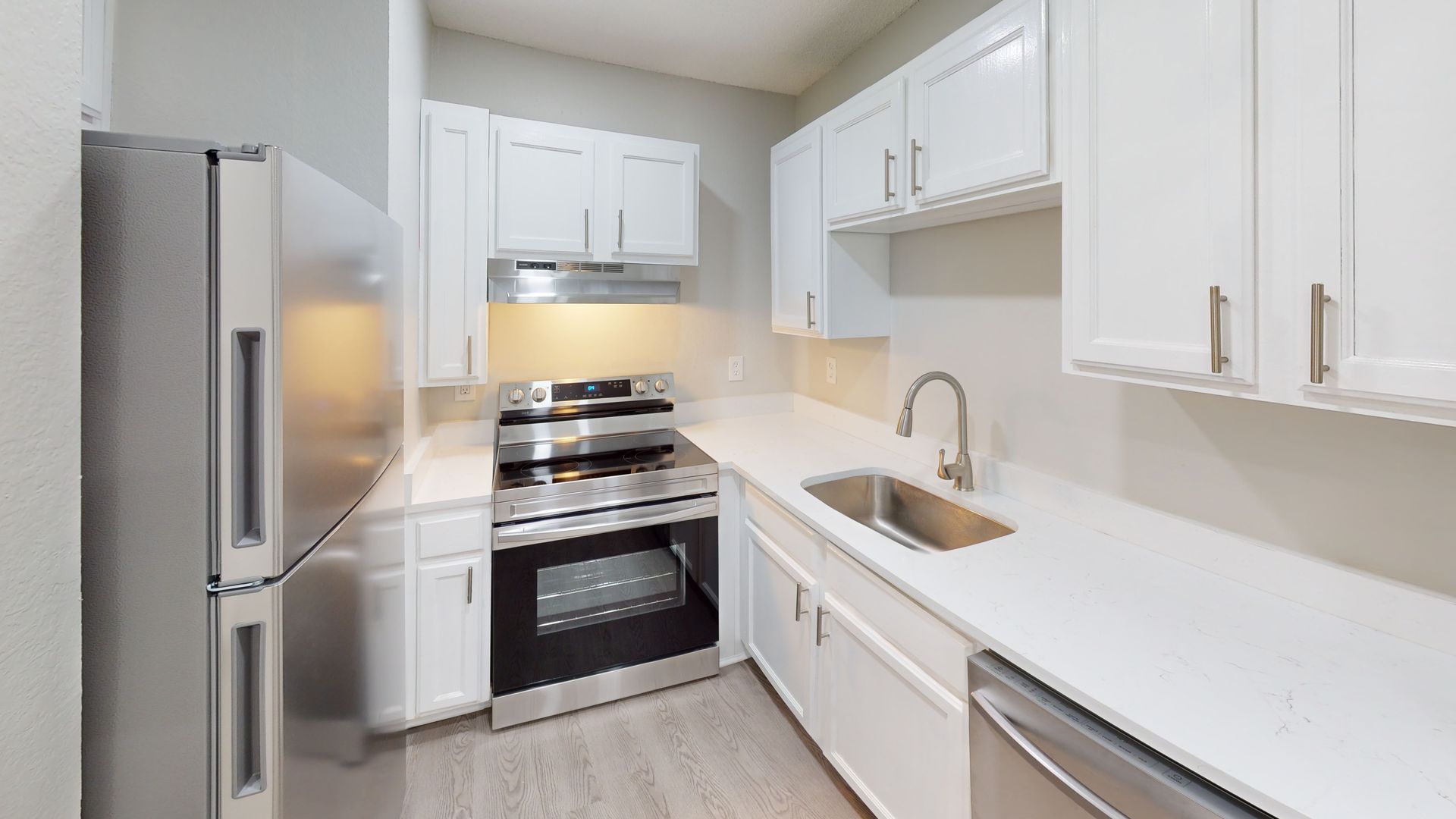 Bright white galley kitchen with stainless steel appliances and a small sink.