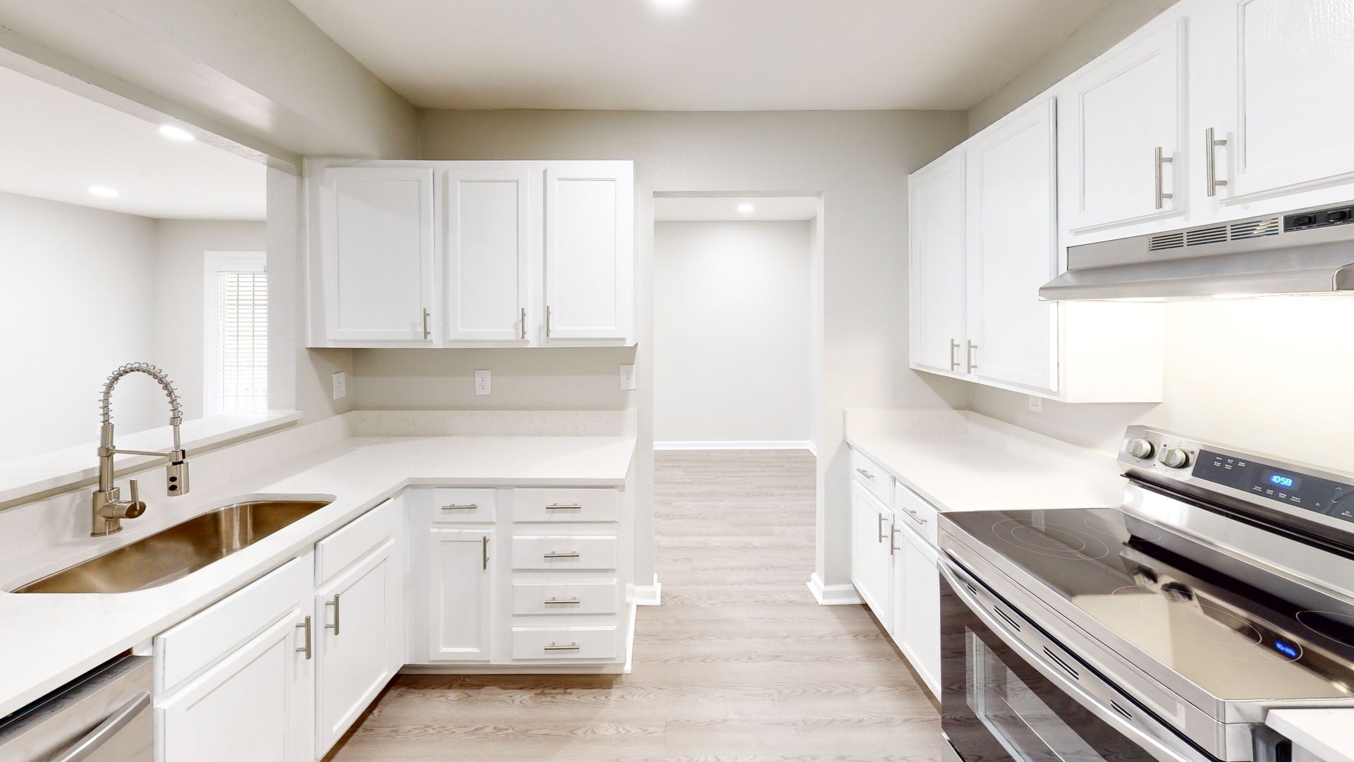 Bright white modern kitchen with stainless steel appliances, wood counters, and light wood flooring