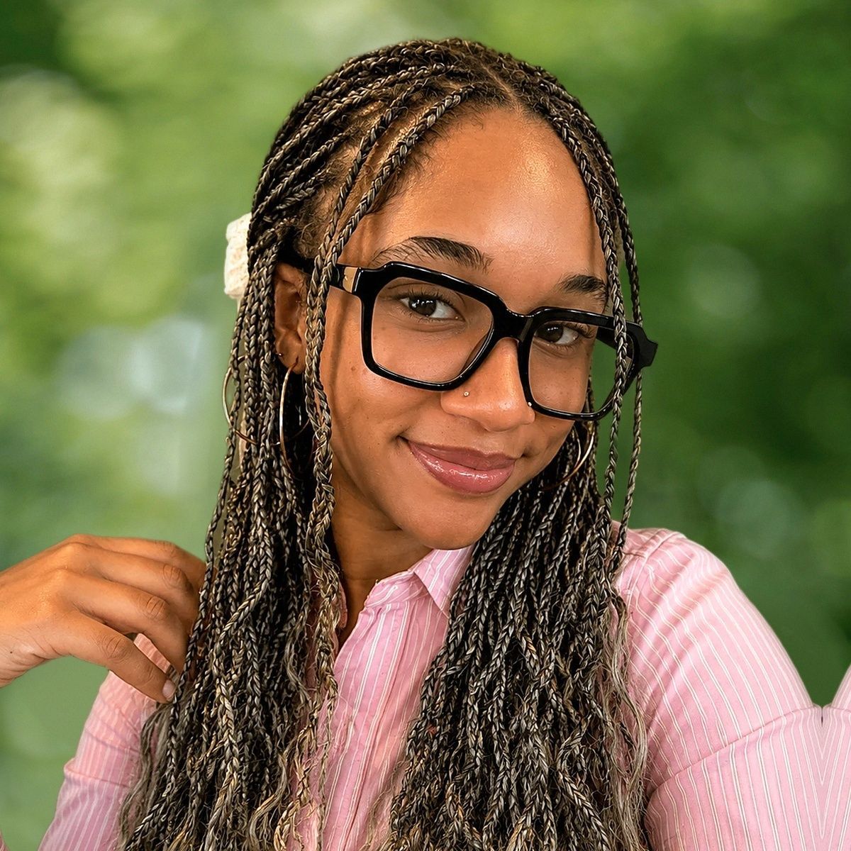 Smiling woman in a black-and-white striped top standing in a sunlit forest