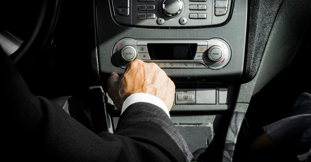 A man in a suit is driving a car and adjusting the climate control.
