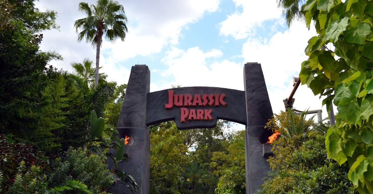 A sign for jurassic park is surrounded by trees
