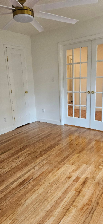 Empty room with white walls, wood flooring, and a white door with window panes.