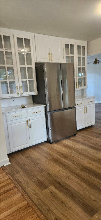 Modern kitchen with stainless steel refrigerator, white cabinets, and wood flooring; image is rotated sideways