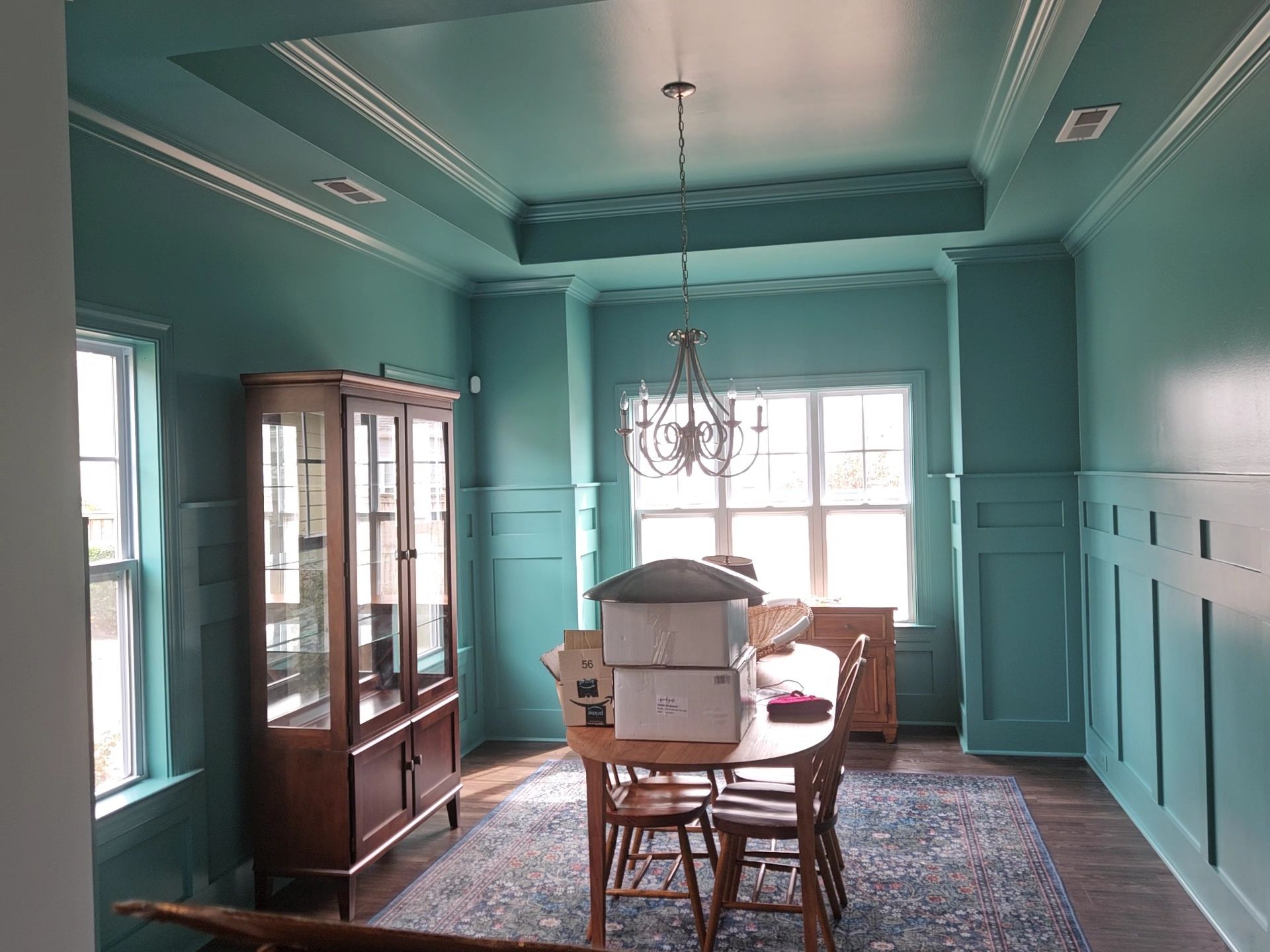 Teal dining room with a table, chairs, chandelier, and built-in cabinet.