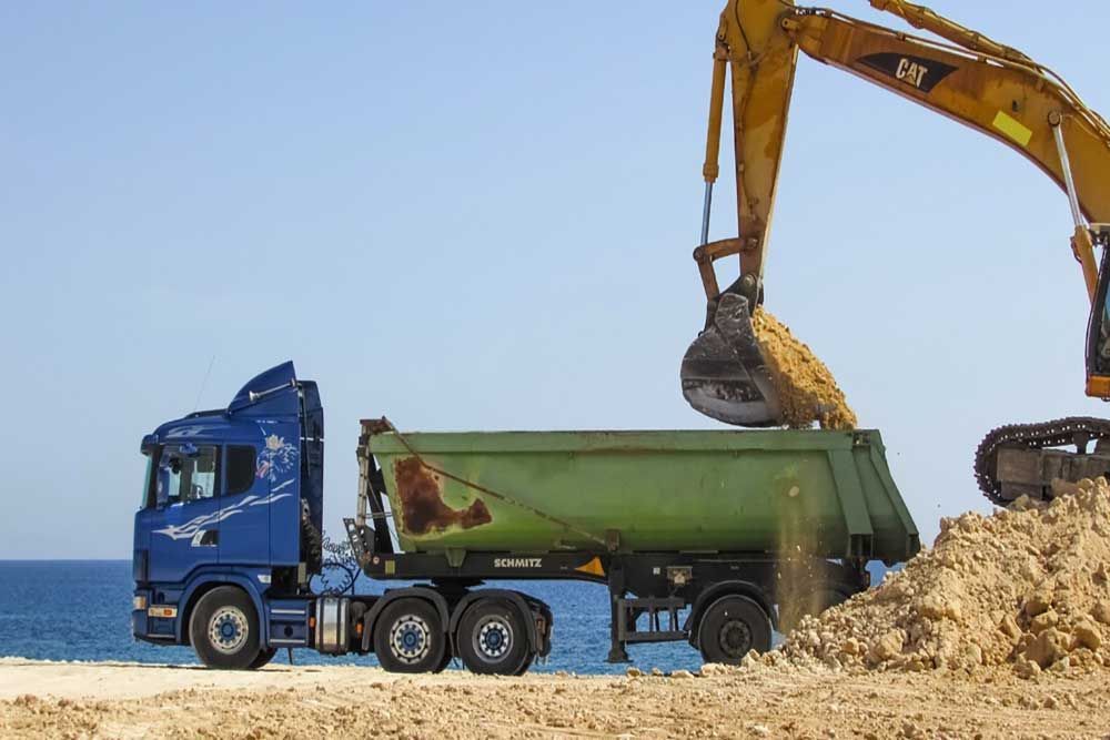 An Excavator Is Loading Dirt Into A Dump Truck — Andrew Johnston Haulage In Tweed Heads, NSW