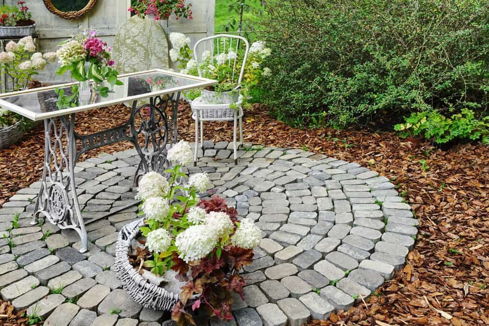 A Table and Chairs Are Sitting on a Brick Patio in a Garden — Andrew Johnston Haulage In Mullumbimby, NSW