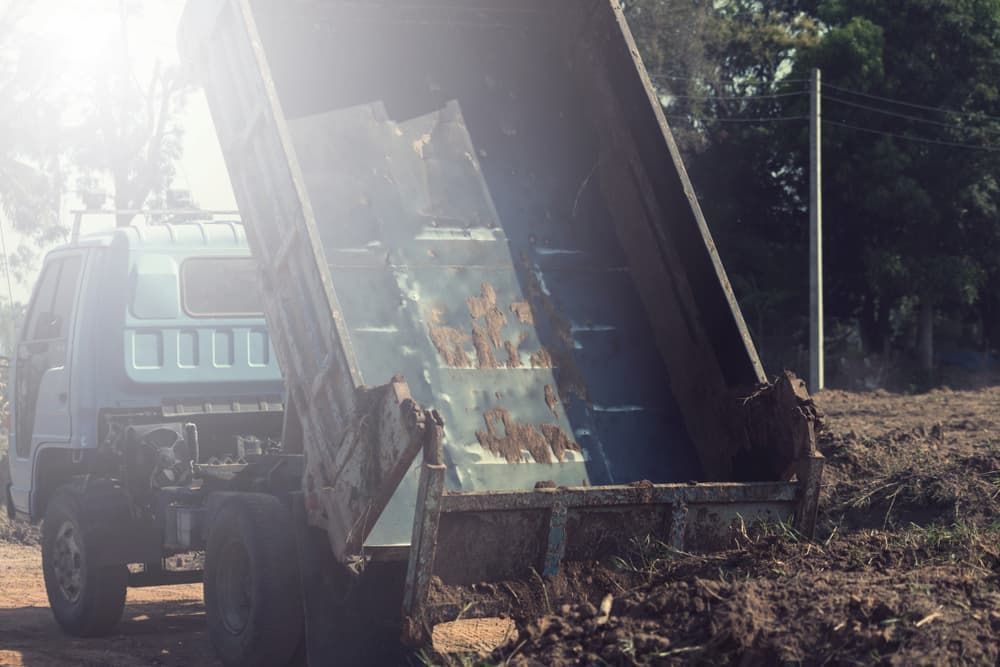 A Dump Truck is Driving Down a Dirt Road — Andrew Johnston Haulage In Kyogle, NSW