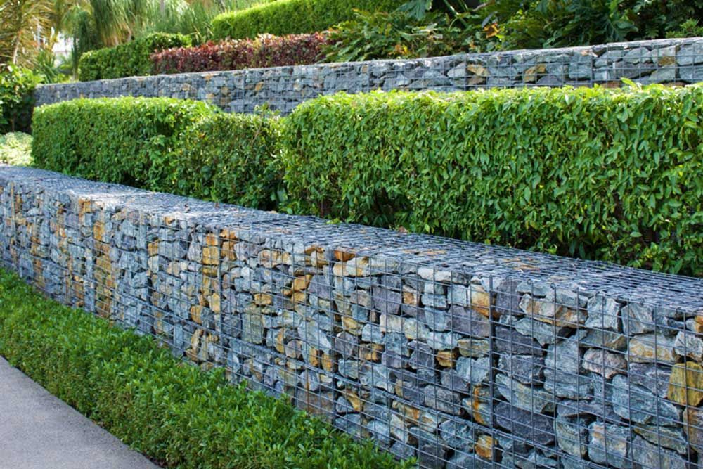 A Fence Made Of Rocks And Wire Is Surrounded By Bushes — Andrew Johnston Haulage In Casino, NSW