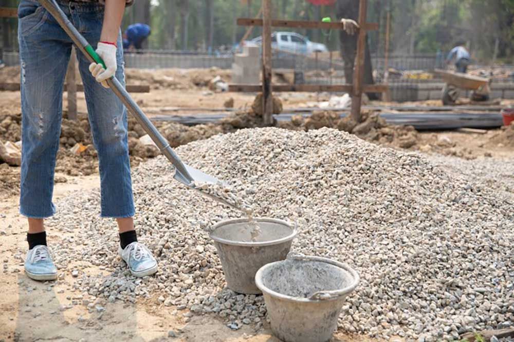 A Person Is Using A Shovel To Dig A Pile Of Gravel — Andrew Johnston Haulage In Casino, NSW
