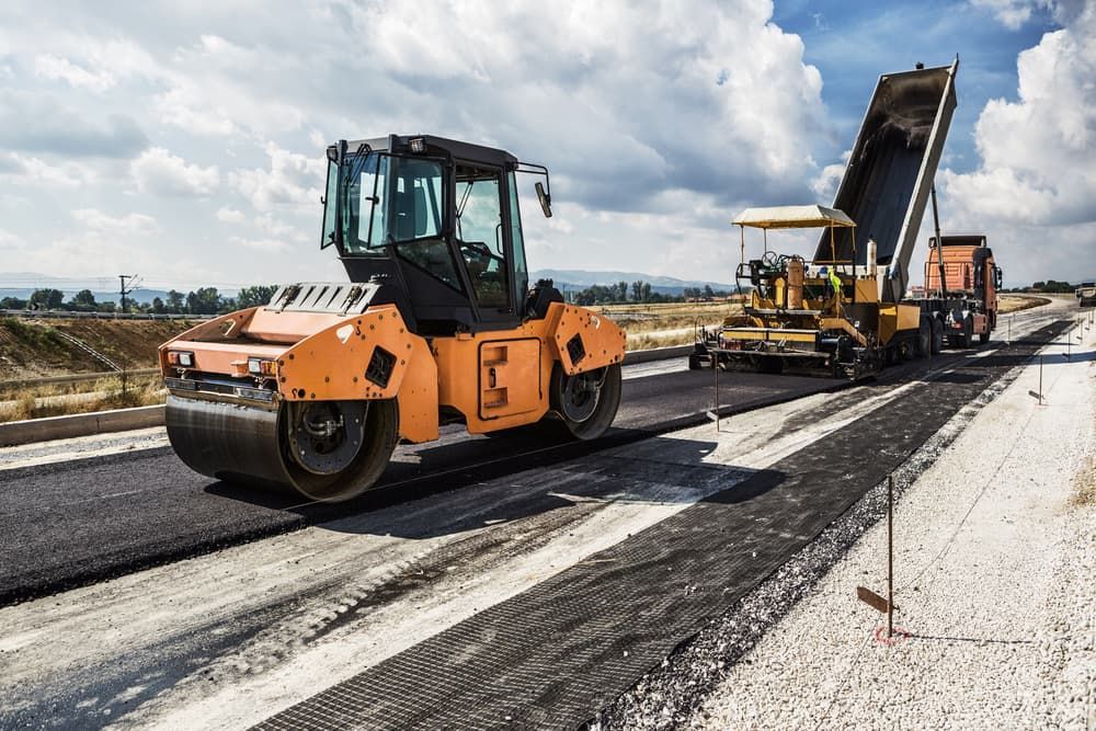 A Road Is Being Paved With A Roller And A Dump Truck — Andrew Johnston Haulage In Byron Bay, NSW