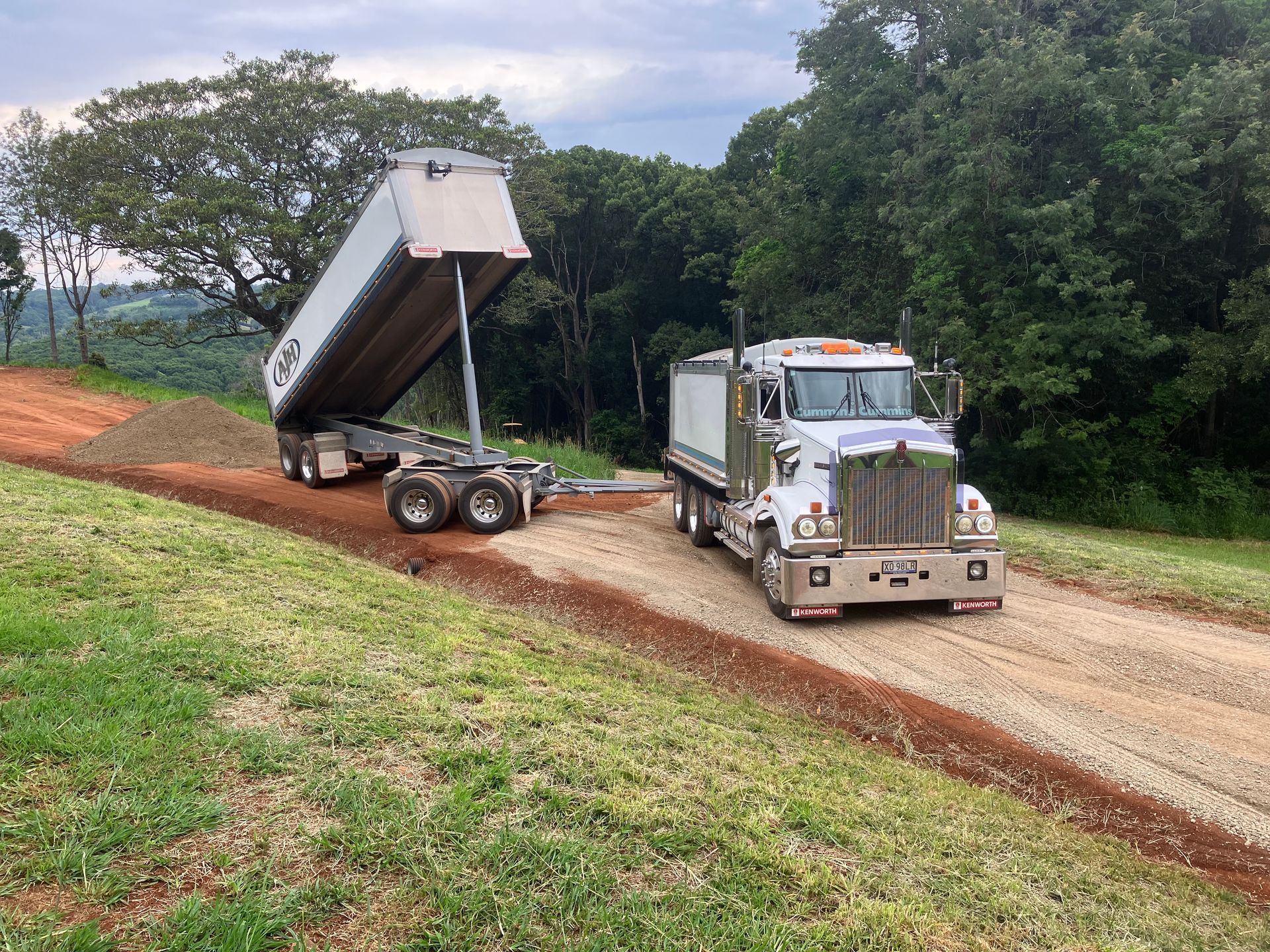 A Dump Truck is Driving Down a Dirt Road — Andrew Johnston Haulage In Ewingsdale, NSW