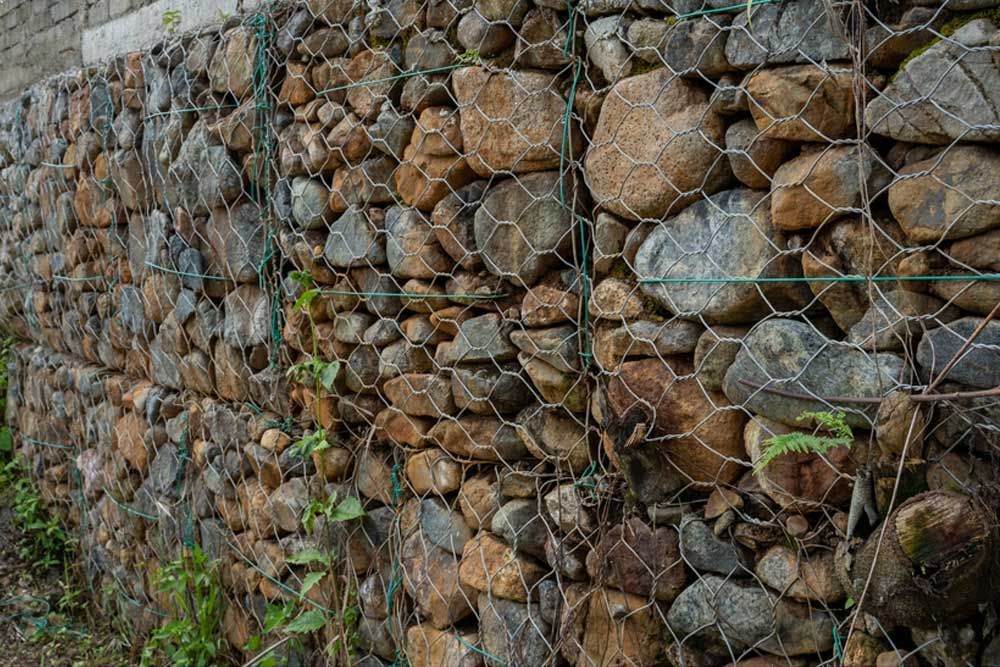 A Stone Wall With A Wire Fence Around It — Andrew Johnston Haulage In Ballina, NSW