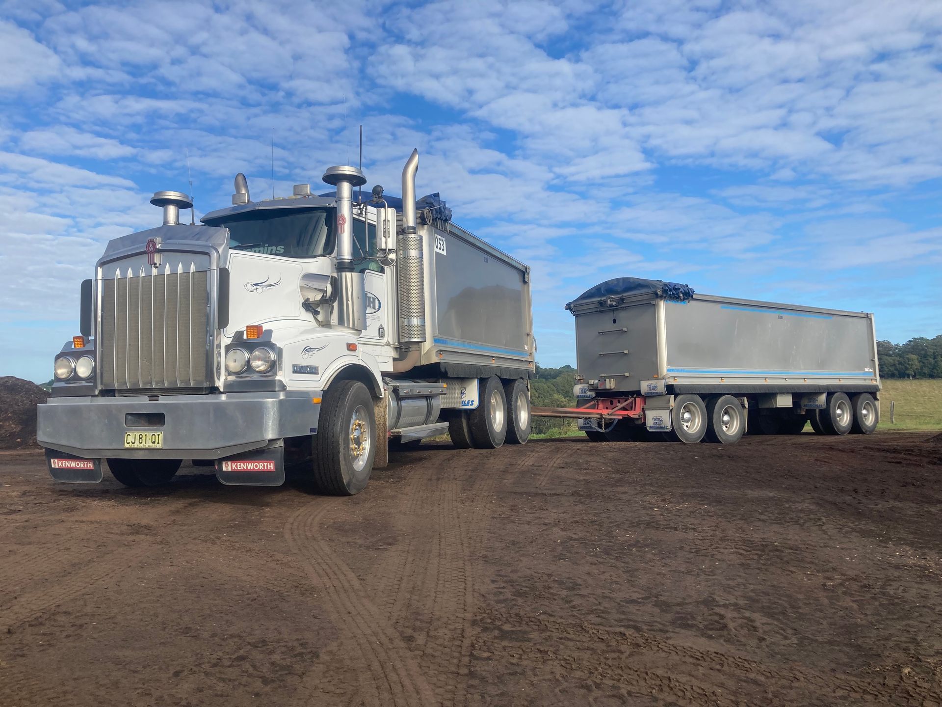 A Dump Truck With a Trailer Attached to It is Parked on a Dirt Road — Andrew Johnston Haulage In Ewingsdale, NSW