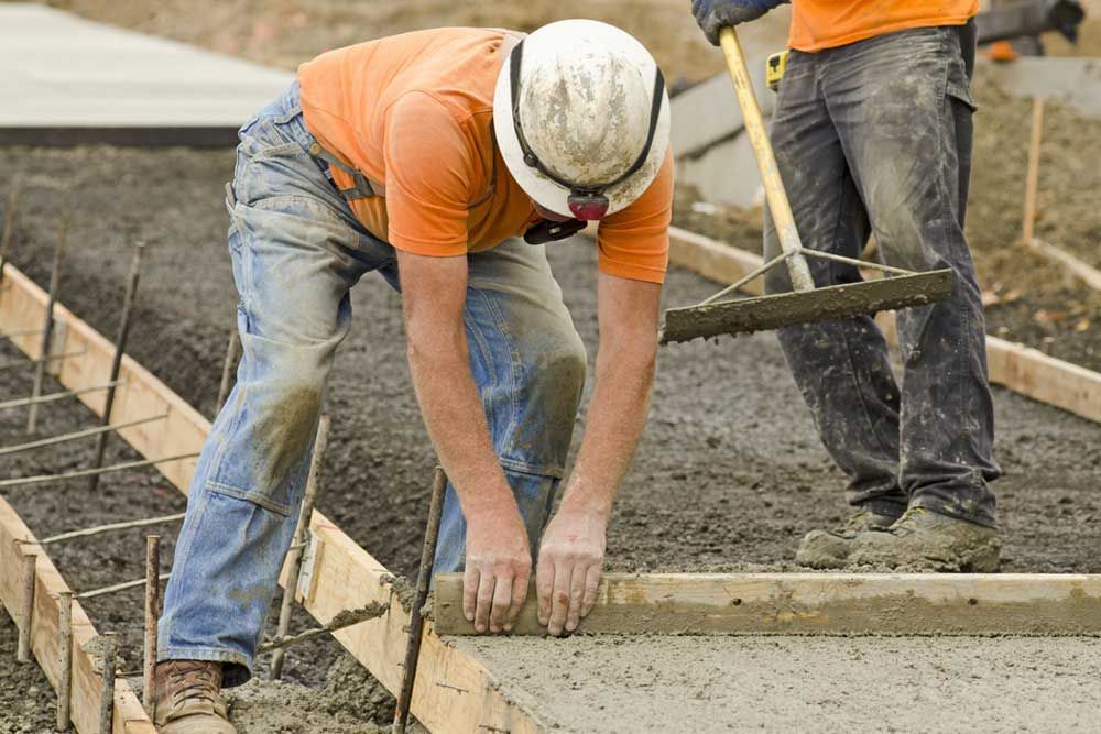 A Man Wearing A Hard Hat Is Working On Concrete — Andrew Johnston Haulage In Byron Bay, NSW