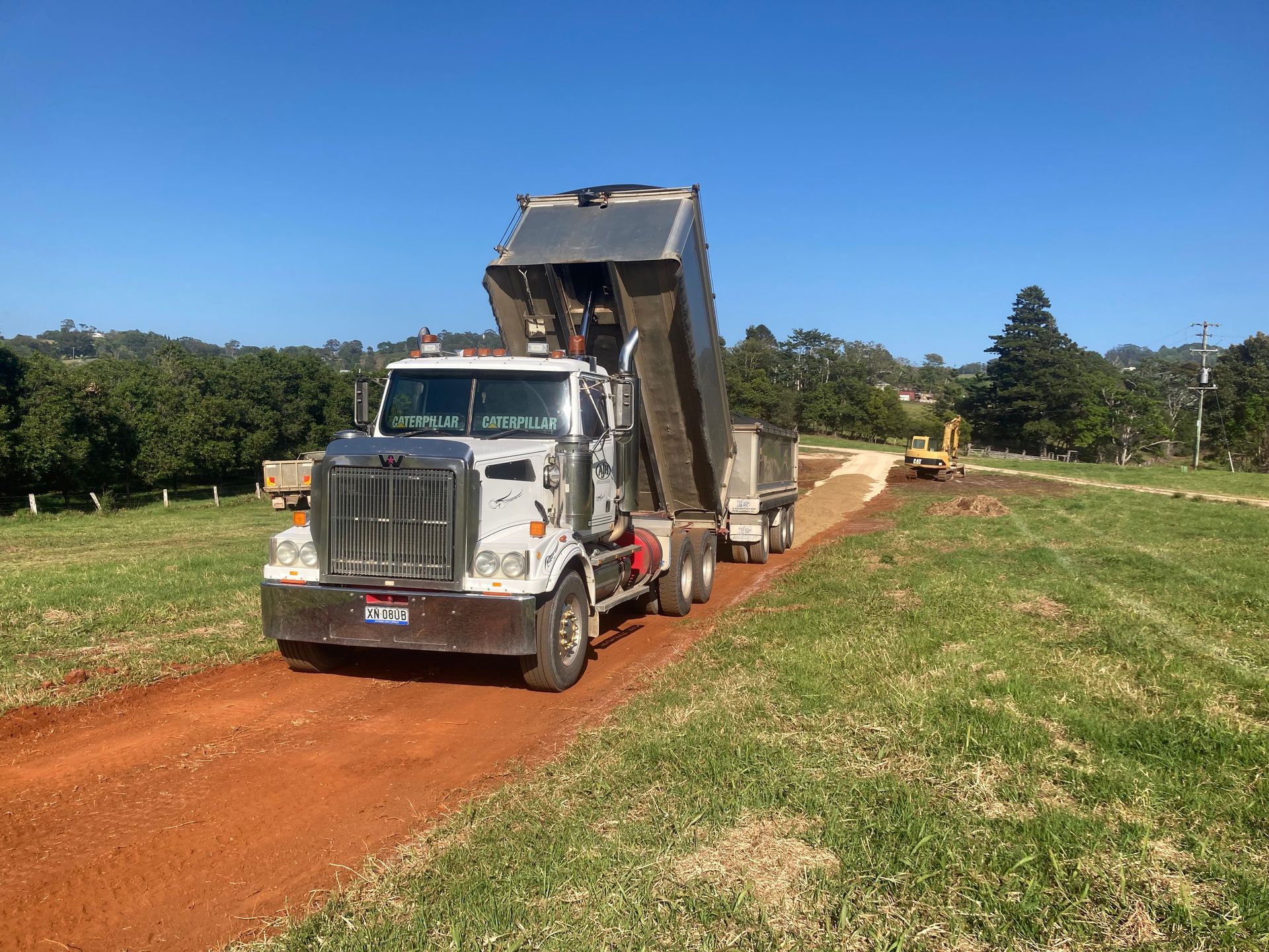 A Dump Truck is Driving Down a Dirt Road in a Field — Andrew Johnston Haulage In Byron Bay, NSW