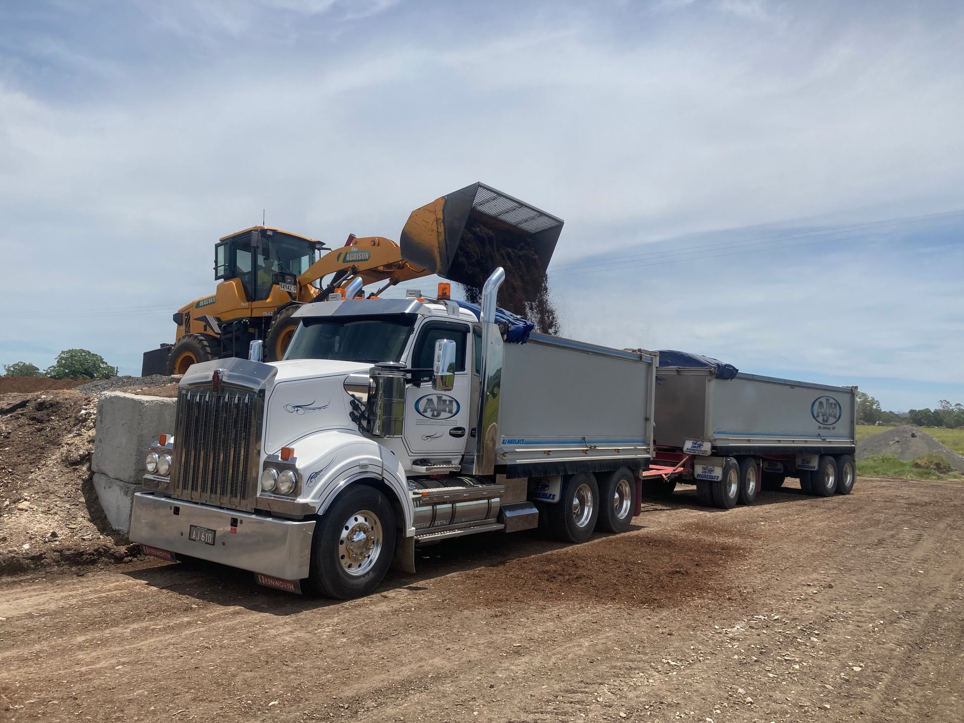 A Dump Truck is Parked on the Side of the Road Next to a Bulldozer — Andrew Johnston Haulage In Ewingsdale, NSW