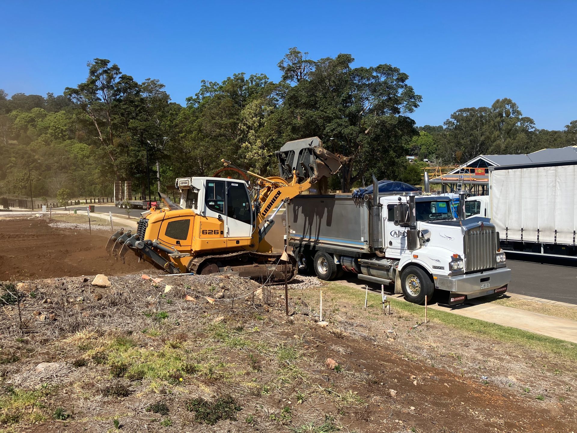 A Bulldozer is Loading Dirt Into a Dump Truck — Andrew Johnston Haulage In Ewingsdale, NSW