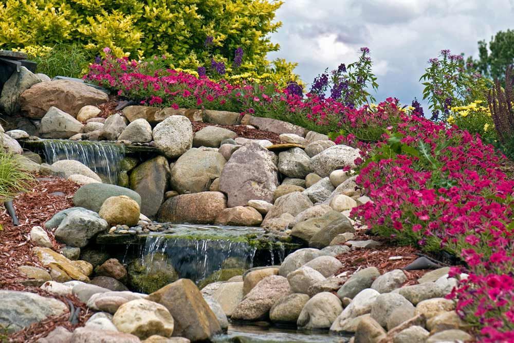 A Waterfall Surrounded By Rocks And Pink Flowers — Andrew Johnston Haulage In Tweed Heads, NSW