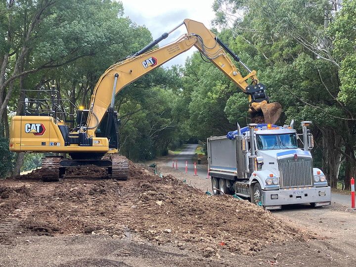 A Yellow Excavator is Loading Dirt Into a Dump Truck — Andrew Johnston Haulage In Murwillumbah, NSW