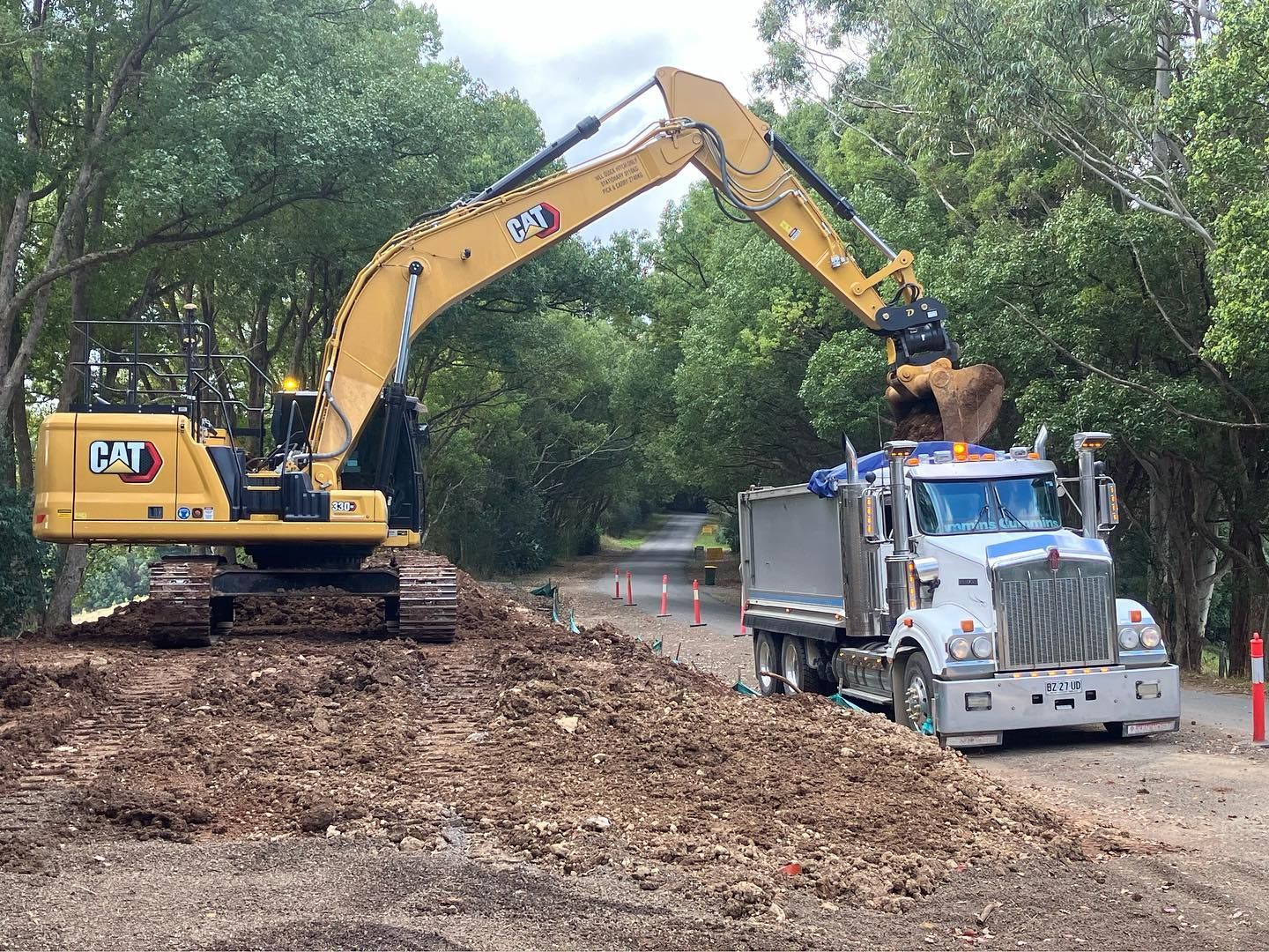 A Large Excavator is Loading Dirt Into a Dump Truck — Andrew Johnston Haulage In Ewingsdale, NSW