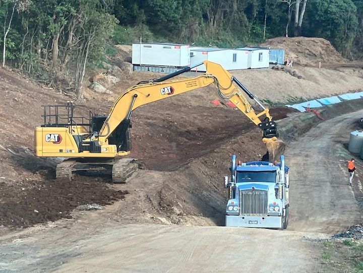 A Bulldozer is Loading Dirt Into a Truck on a Dirt Road — Andrew Johnston Haulage In Casino, NSW