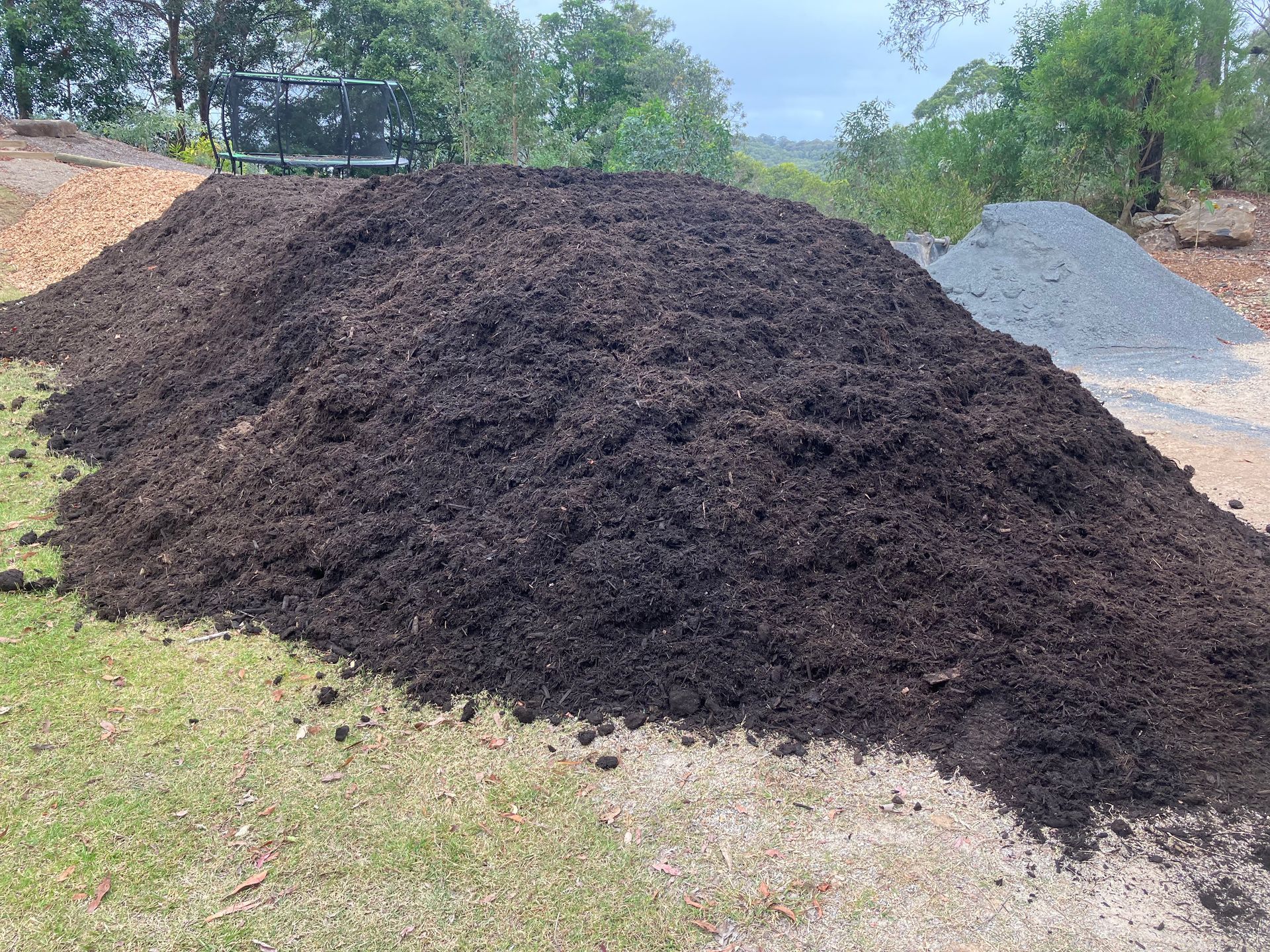 A Large Pile of Dirt is Sitting on Top of a Lush Green Field — Andrew Johnston Haulage In Ewingsdale, NSW