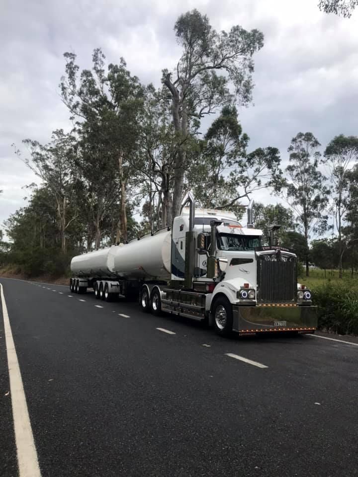 A Kenworth Semi Truck Is Driving Down A Road — Andrew Johnston Haulage In Ewingsdale, NSW