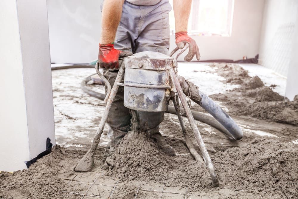 A Man Wearing Red Gloves Is Working On A Concrete Floor — Andrew Johnston Haulage In Byron Bay, NSW