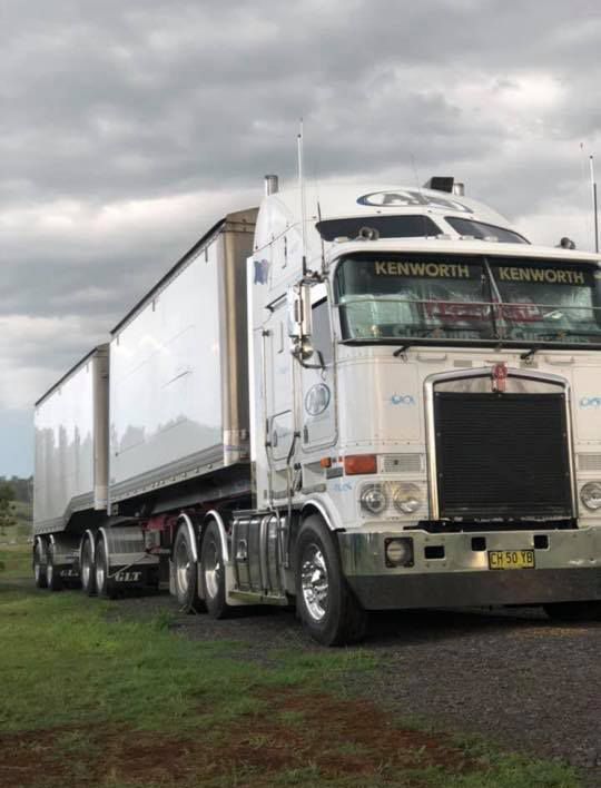 A Semi Truck Is Parked In A Grassy Field — Andrew Johnston Haulage In Ewingsdale, NSW