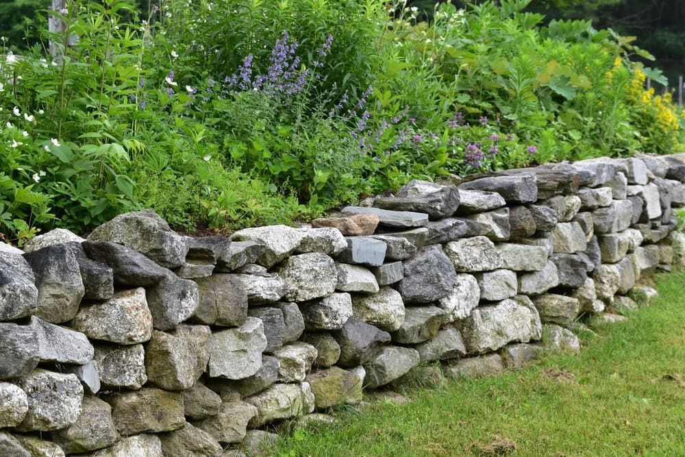 A Stone Wall Surrounded By Plants And Flowers In A Garden — Andrew Johnston Haulage In Kyogle, NSW