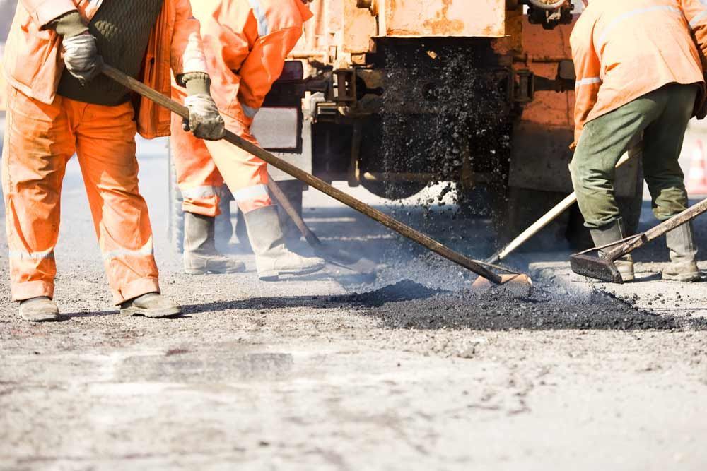 A Group Of Construction Workers Are Working On A Road — Andrew Johnston Haulage In Gold Coast, QLD