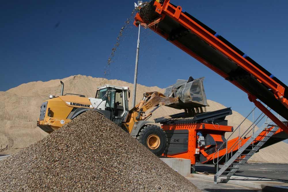 A Tractor Is Loading Gravel Into A Conveyor Belt — Andrew Johnston Haulage In Tweed Heads, NSW