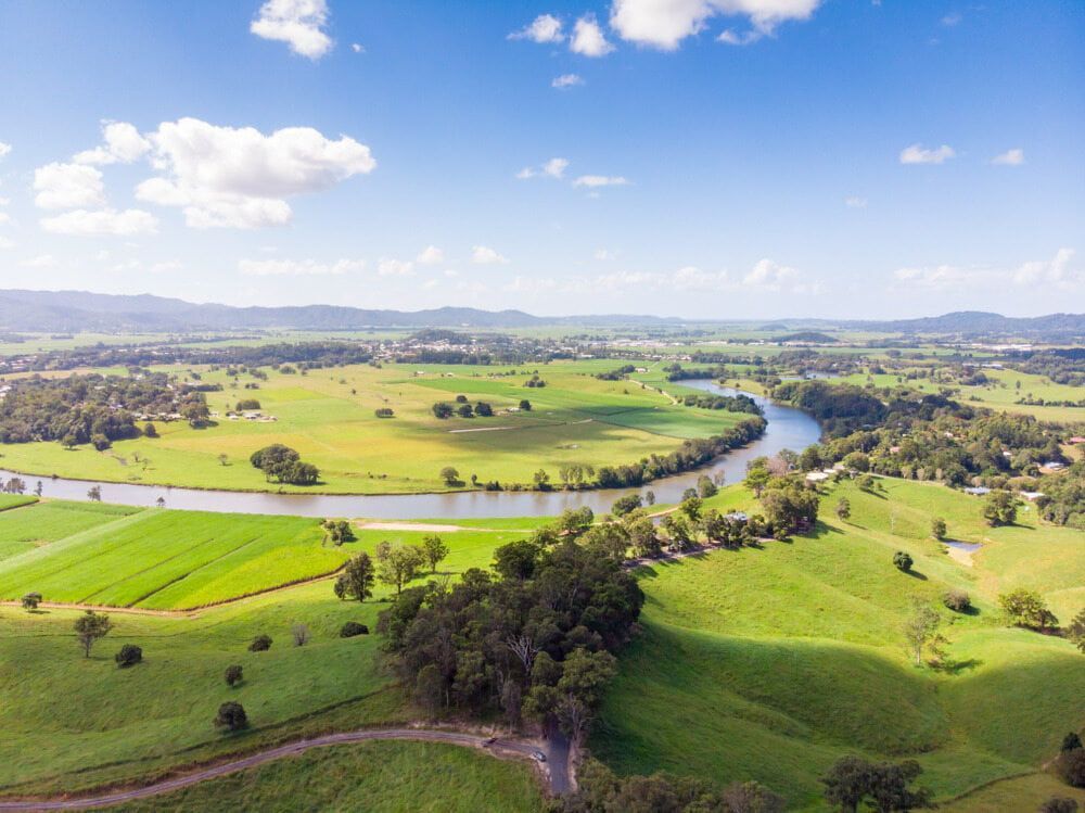 An Aerial View of a River Surrounded by Green Fields and Trees — Andrew Johnston Haulage In Murwillumbah, NSW