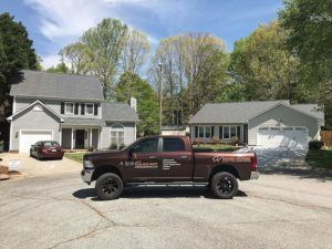 Maroon pickup truck parked in a suburban driveway with houses and trees in the background