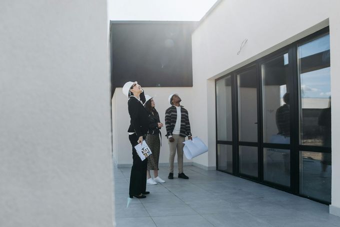 Two people standing outside a modern building with glass doors and white walls