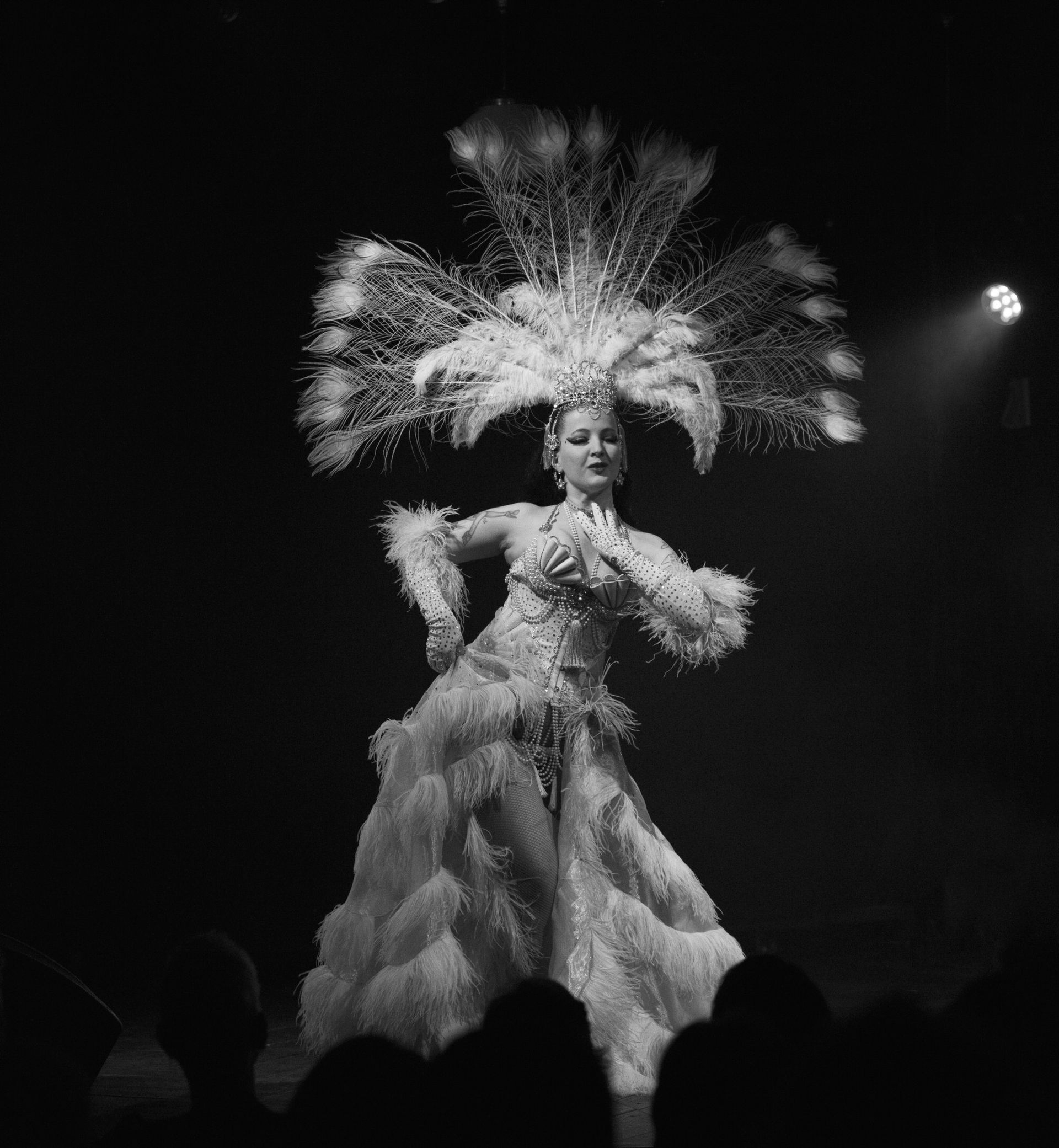 Une danseuse vêtue d'un costume et d'une coiffe blancs somptueux, se produit sur scène.