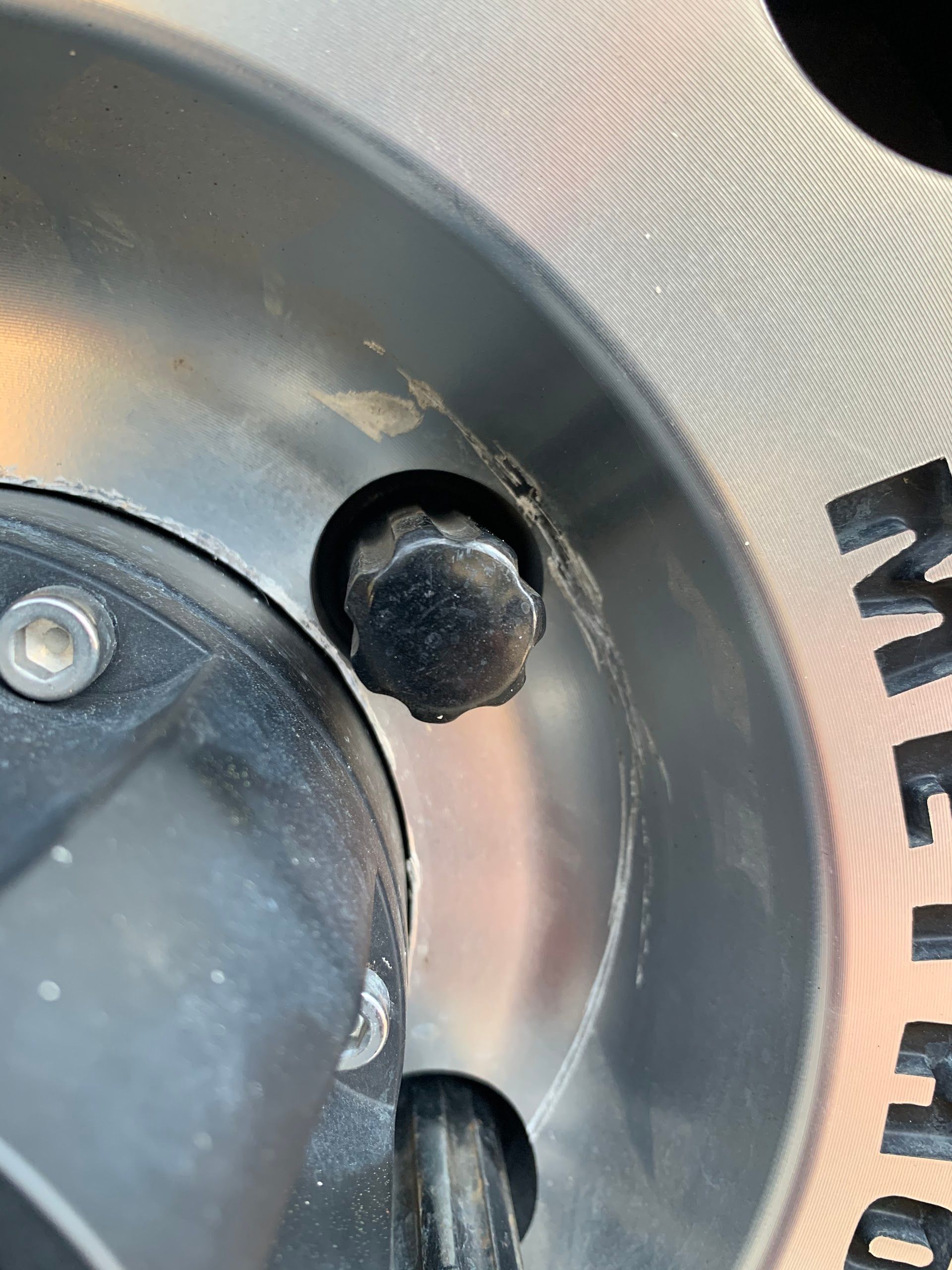 Close-up of a metal wheel hub with a black rubber valve stem cap and silver rim. | Complete Car Care Auto Sales & Service