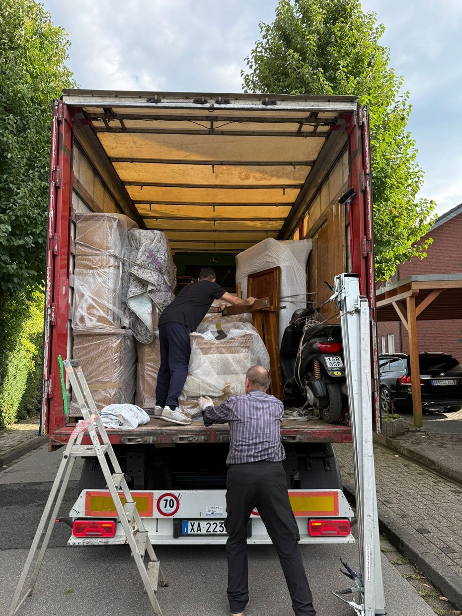 Persone che caricano mobili imballati su un camion per traslochi dal vialetto di una casa