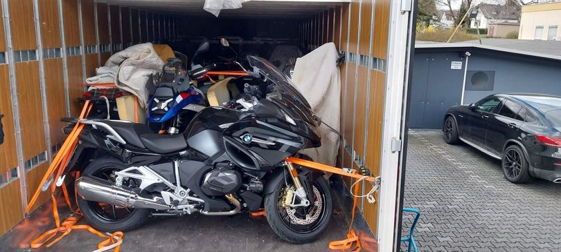 Motocicletta legata in un container accanto a un'auto nera in un parcheggio