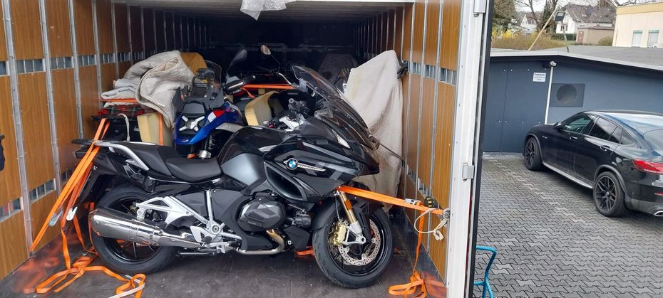 Motocicletta legata in un container accanto a un'auto nera in un parcheggio