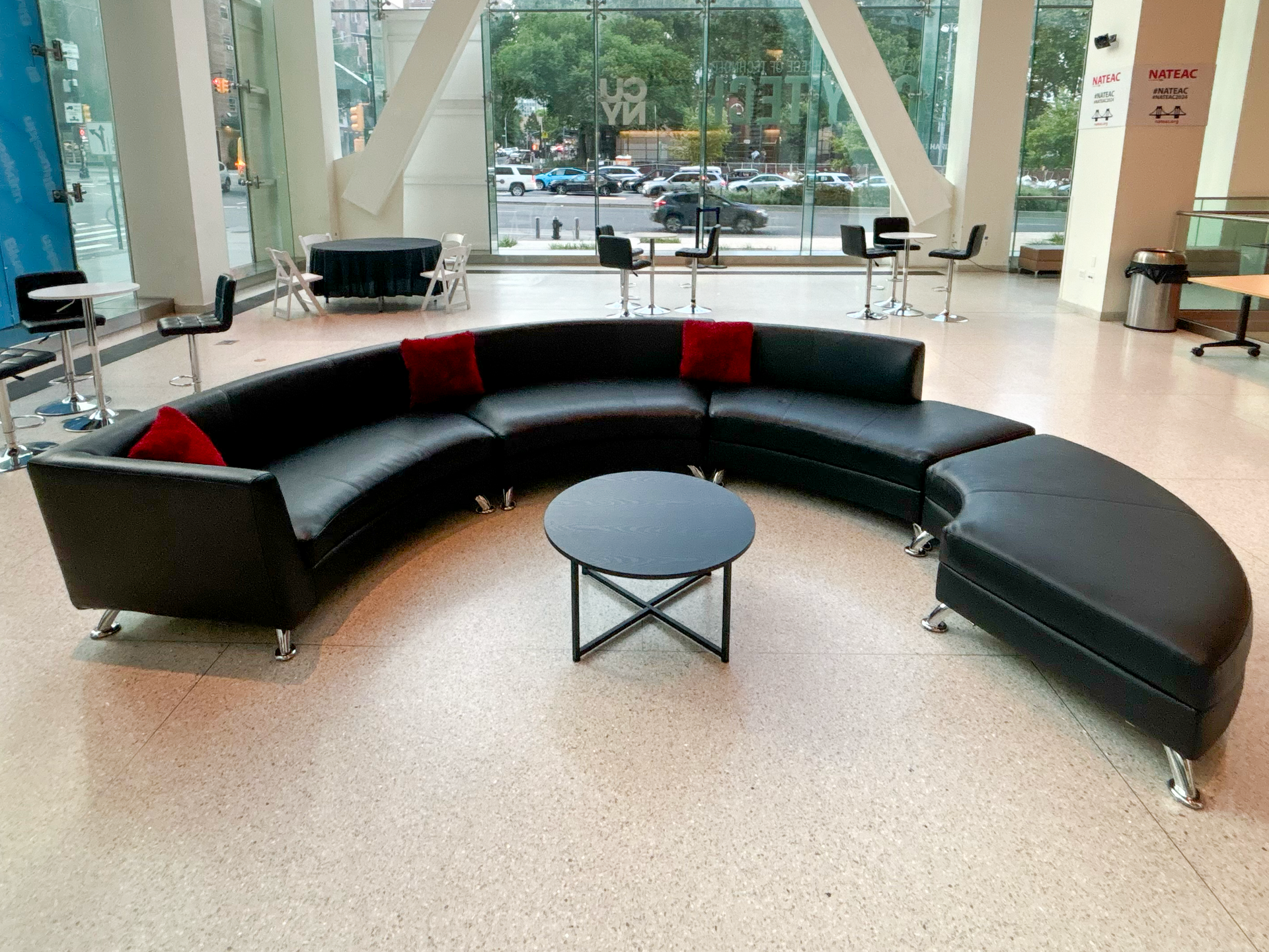 A curved black leather couch with a coffee table
