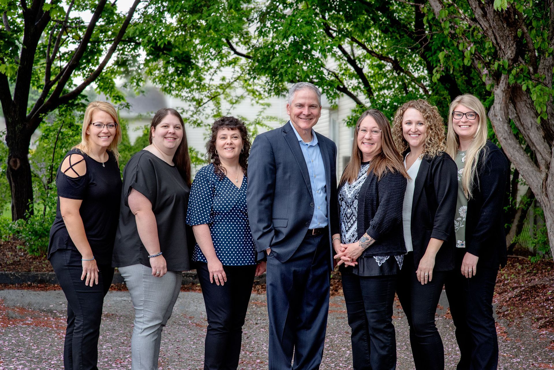 A group of people standing next to each other in front of trees.