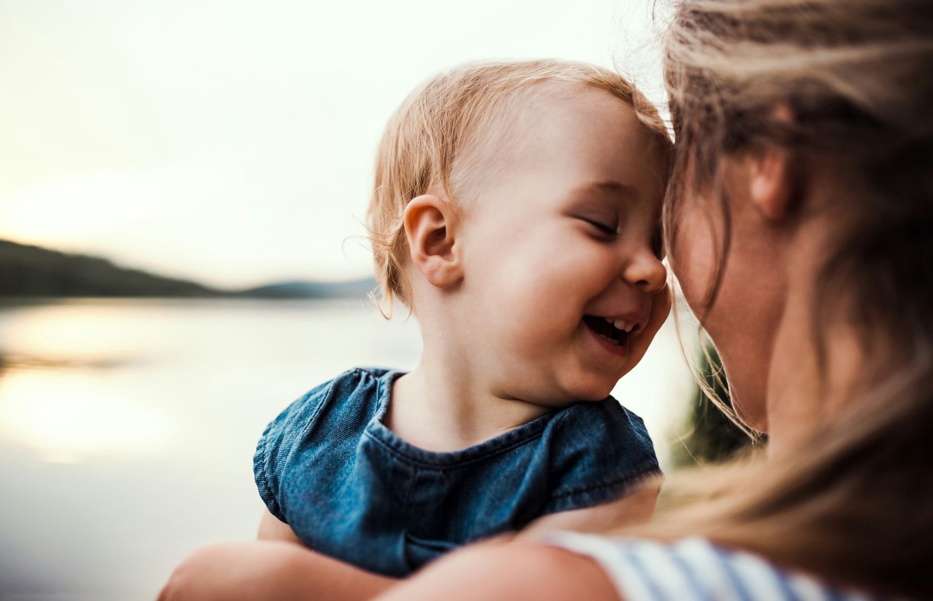 A woman is holding a baby in her arms and the baby is smiling.